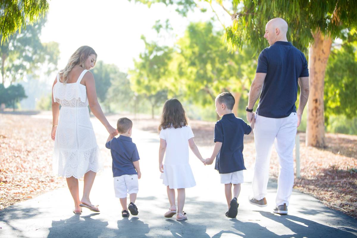 Family with three children walking in summer park together